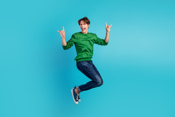 Full body photo of cheerful ecstatic rock fan showing you rock horned fingers signs jumping isolated blue background