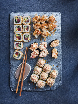 Selection of Japanese appetizing gunkan and maki rolls with fresh and flaked tuna on dark background