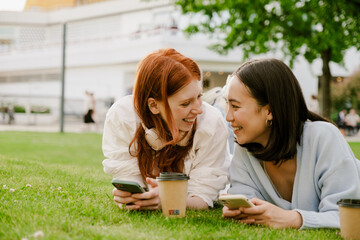 Young multinational women drinking coffee and using cellphone