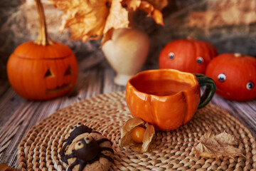 Traditional autumn Halloween cookies and cup of tea among pumpkins