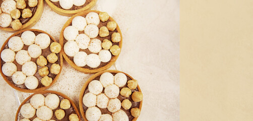 French traditional hazelnut creamy tarts in the row. Vintage background. Copy space. Extra wide...