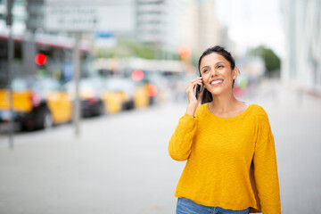 smiling woman walking with cellphone in city
