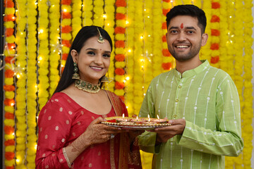 Happy Young couple celebrating diwali holding plate of diyas