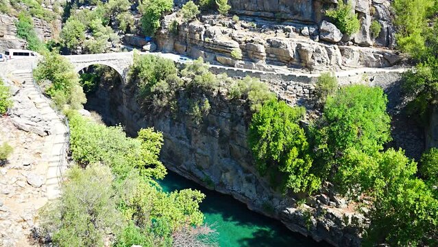 Ancient arch bridge over the Koprucay river gorge in Koprulu national Park in Turkey. Panoramic scenic view of the canyon and blue stormy mountain river