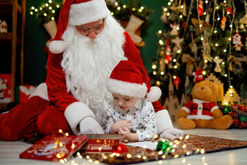 Cute child drawing with Santa Clause while lying on the floor near Christmas tree. New Year concept 