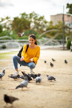 Happy Woman Feeding Pigeons In Park