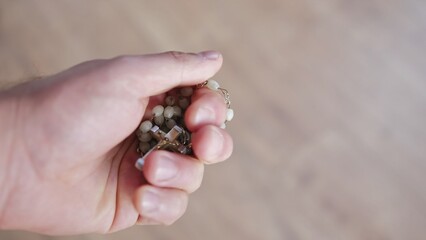Hand of Christian Catholic Caucasian Male Praying with Holy Rosary