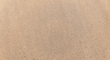 Fototapeta na wymiar Texture of yellow compressed sand on the beach