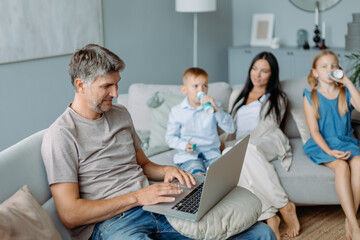 smiling father using a laptop in a cozy living room.
