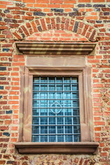 Brick wall of an old building with a window with a lattice