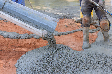 Concrete contractor pours wet concrete during the paving driveway while he is working on it
