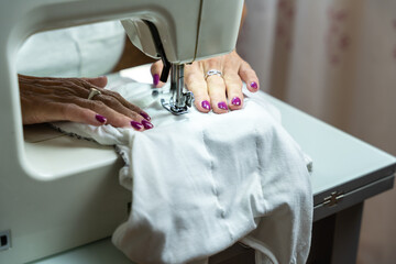 Close-up of the hands of an unrecognizable woman sewing on her sewing machine.