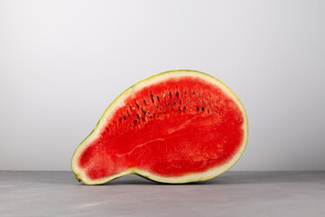 Fototapeta na wymiar Half of pear-shaped watermelon. Deformed ugly watermelon. Red pulp and seeds. Concept - Food waste reduction. Eating imperfect foods