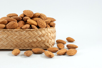Almonds are placed in a wicker container and put on a white background, space for text.