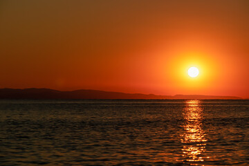 Panoramic view of sunset over Aegean Mediterranean Sea seen from Karydi beach, peninsula Sithonia, Chalkidiki (Halkidiki), Greece, Europe. Romantic atmosphere, reflection of the sunbeams on surface