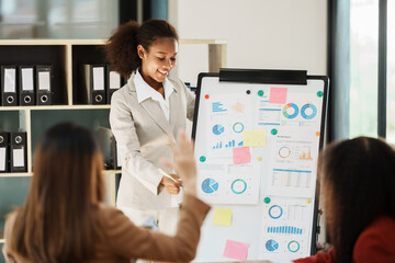 African businesswoman giving presentation on flip chart discussing new marketing research results with executive team in boardroom, black employee reporting about project at meeting