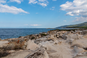 Rocky seashore before sunset near Karydi beach, peninsula Sithonia, Chalkidiki (Halkidiki), Greece, Europe. Distant scenic view of Mount Athos. Rock formations along Aegean Mediterranean coastline