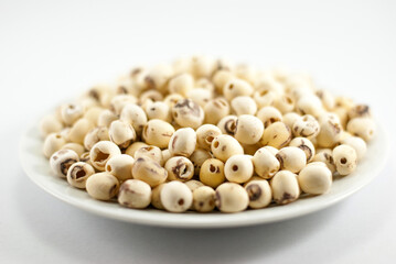 Dried lotus seeds in white plate on white background, selective focus.