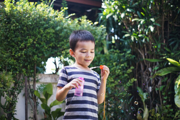 Little boy with soap bubbles in summer park.
