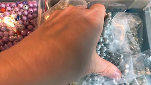 main avec des perles dans un sac. perles nacr&eacute;es pour cr&eacute;ation et fabrication bijoux et accessoires 