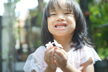 Obraz premium cute little asian girl holding a white bouquet. Child planting spring flowers. 