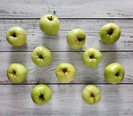 Scattered green apples on light wooden background, top view, flat lay.
