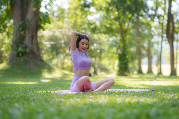 Naklejka na ściany i meble Yoga in the park. Young Asian woman practicing yoga pose at the park.