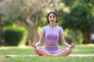 Yoga in the park. Young Asian woman practicing yoga pose at the park.