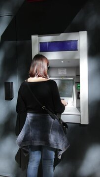 femme qui retire de l'argent &agrave; un guichet automatique