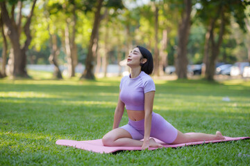 Yoga in the park. Young Asian woman practicing yoga pose at the park.