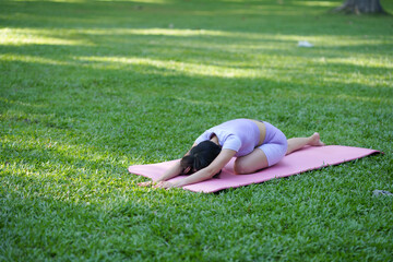 Yoga in the park. Young Asian woman practicing yoga pose at the park.