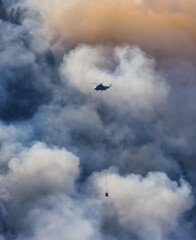 Wildfire Service Helicopter flying over BC Forest Fire and Smoke on the mountain near Hope during a hot sunny summer day. British Columbia, Canada. Natural Disaster