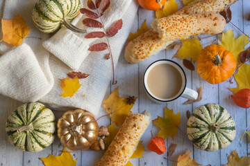 Mug of hot coffee, colorful pumpkins and autumn leaves on a wooden background. Autumn still life.