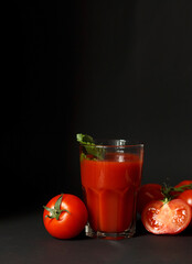 Fresh tomato juice in a glass with tomatoes on a dark background. Vegetable tomato drink for a healthy diet on background.