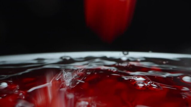 Pomegranate seeds fall into the red juice, on a black background. slow motion. Dolly slider, extreme close-up.