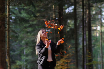 Kobieta podrzucająca liście jesienne.