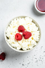 Cottage cheese breakfast bowl with cream and raspberries. Top view, flat lay, copy space.