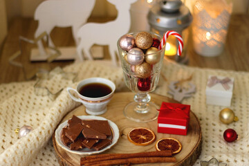 Various Christmas decorations, cup of tea or coffee, sweets, small presents, knitted blanket and candles. Selective focus.