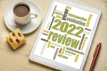 2022 year review word cloud on a digital tablet, flat lay with a cup of coffee, end of year business analysis concept