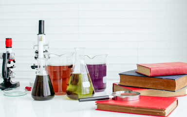Background of microscopes, books, test experimental tube and magnifying glasses on white table for studying science in class. Education Concept.