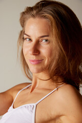 Close-up portrait of beautiful woman looking at camera, posing isolated over grey background. Anti-wrinkles care