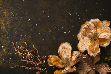 Golden flowers for christmas decorations on black background top view, christmas background with copy space for text