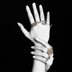 Fashion concept. Abstract studio portrait of beautiful woman hands with manicure and many various fancy rings on her fingers in black studio background. Black and white hands and jewelry is colorful