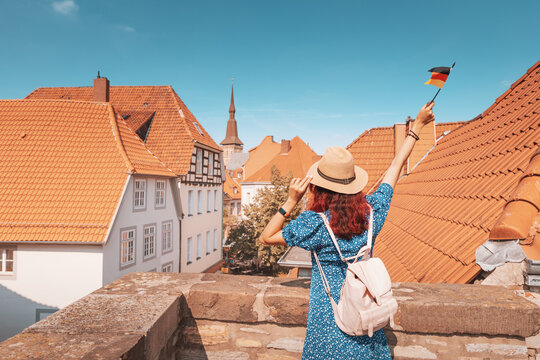 A Young Happy Asian Girl With A German Flag At The Old Town Or Altstadt Viewpoint In Osnabruck. Studying Language Abroad And Traveling Concept