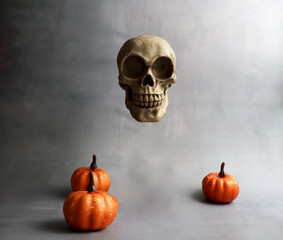 halloween floating skull and pumpkins on grey background