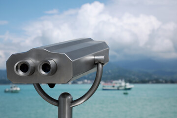 Metal tower viewer installed near sea, space for text. Mounted binoculars