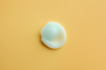 Sample of face cream on yellow background, top view