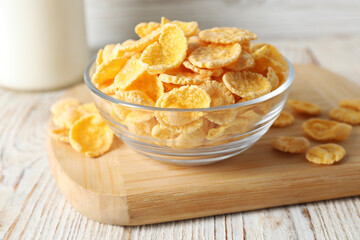 Glass bowl of tasty crispy corn flakes on white wooden table