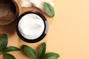 Flat lay composition with jar of coconut face cream on light orange background. Space for text