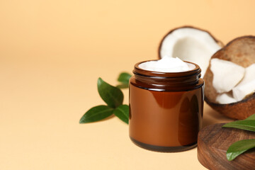 Jar of coconut face cream on light orange background. Space for text